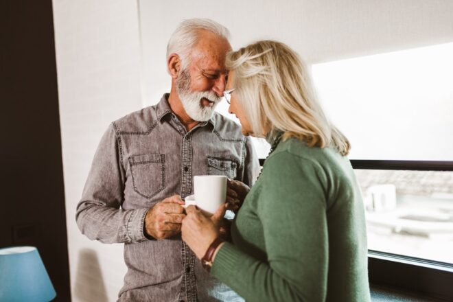 Senior,couple,holding,white,mugs,at,home