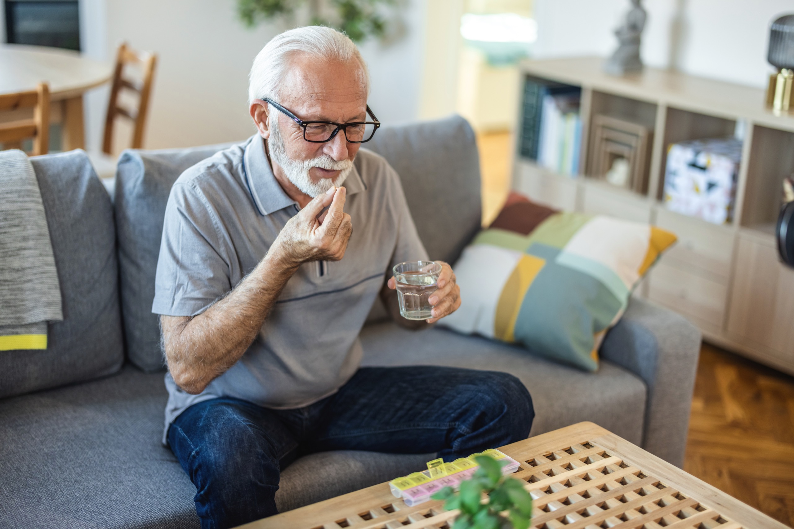 senior man with glass of water taking pill