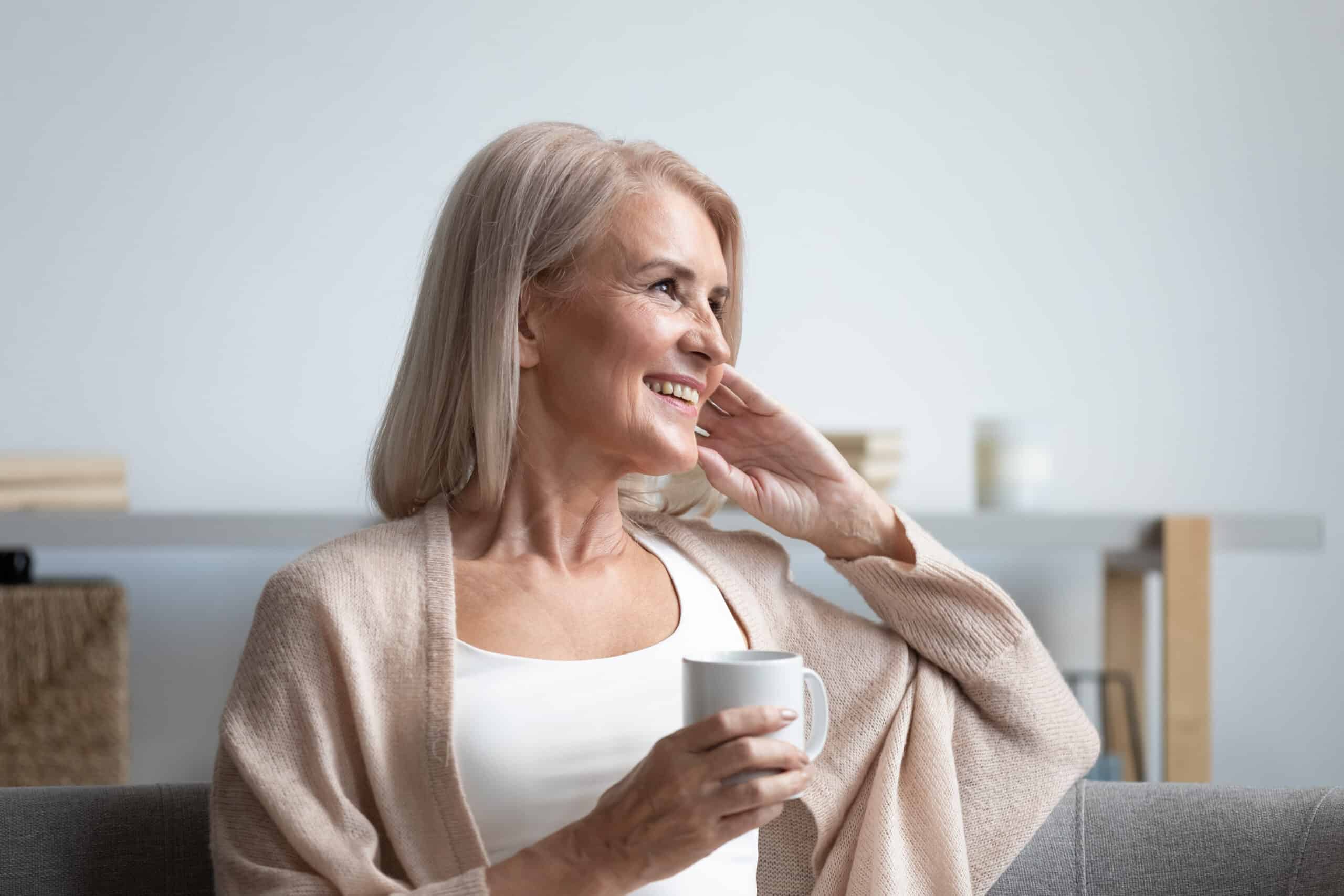 Frau mit Tasse in der Hand laechelt