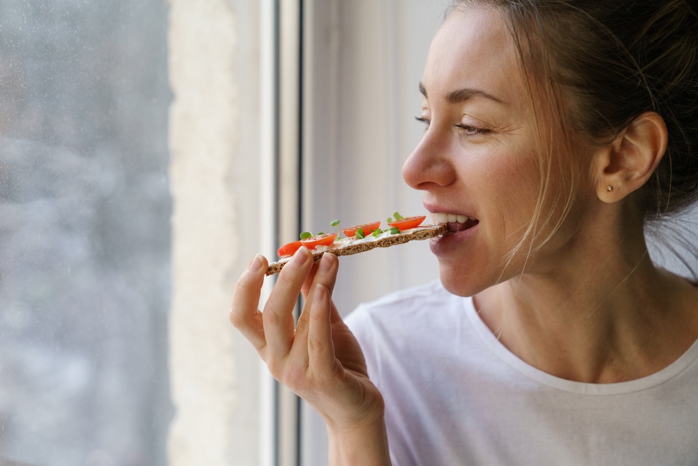 Woman eating a loaf of bread with tomatoes