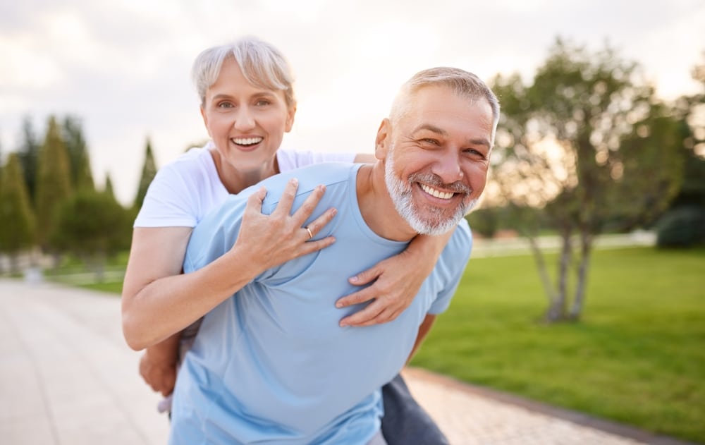 Happy older man with strong prostate carries woman on his back