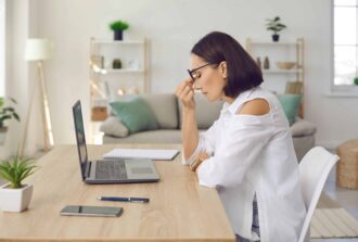 Frau denkt nachund ist gestresst vor dem Laptop